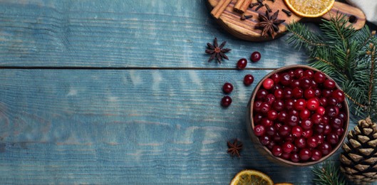 Image of Flat lay composition with fresh ripe cranberries on blue wooden table, space for text. Banner design