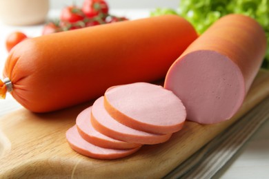 Photo of Board with tasty boiled sausages on white table, closeup