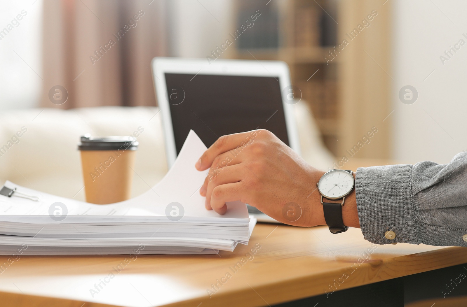 Photo of Man working with documents at wooden table in office, closeup