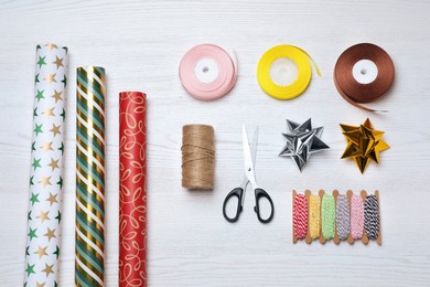 Photo of Flat lay composition with colorful wrapping paper rolls and accessories on white wooden table
