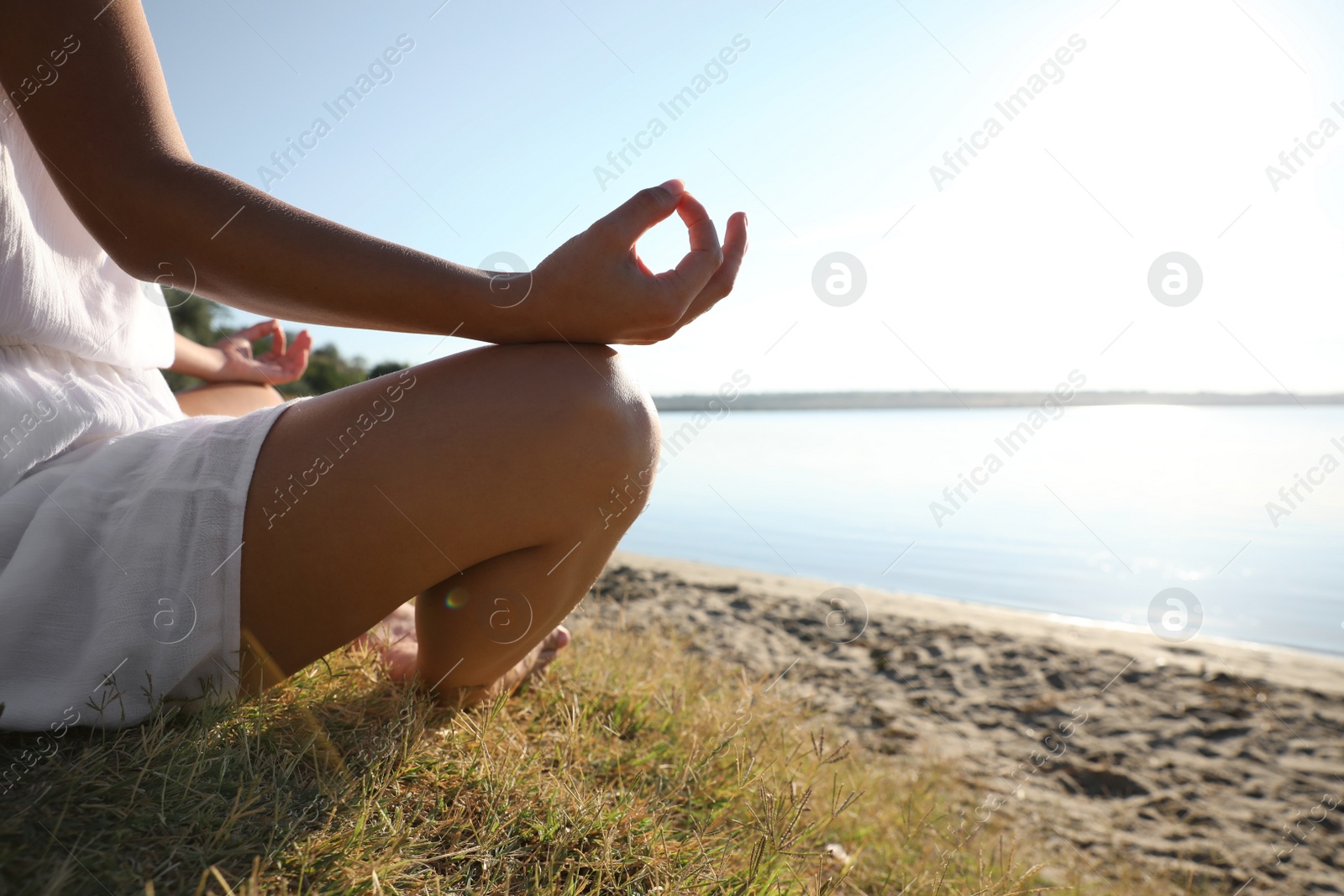 Photo of Young woman meditating near river at sunset, closeup view with space for text. Nature healing power