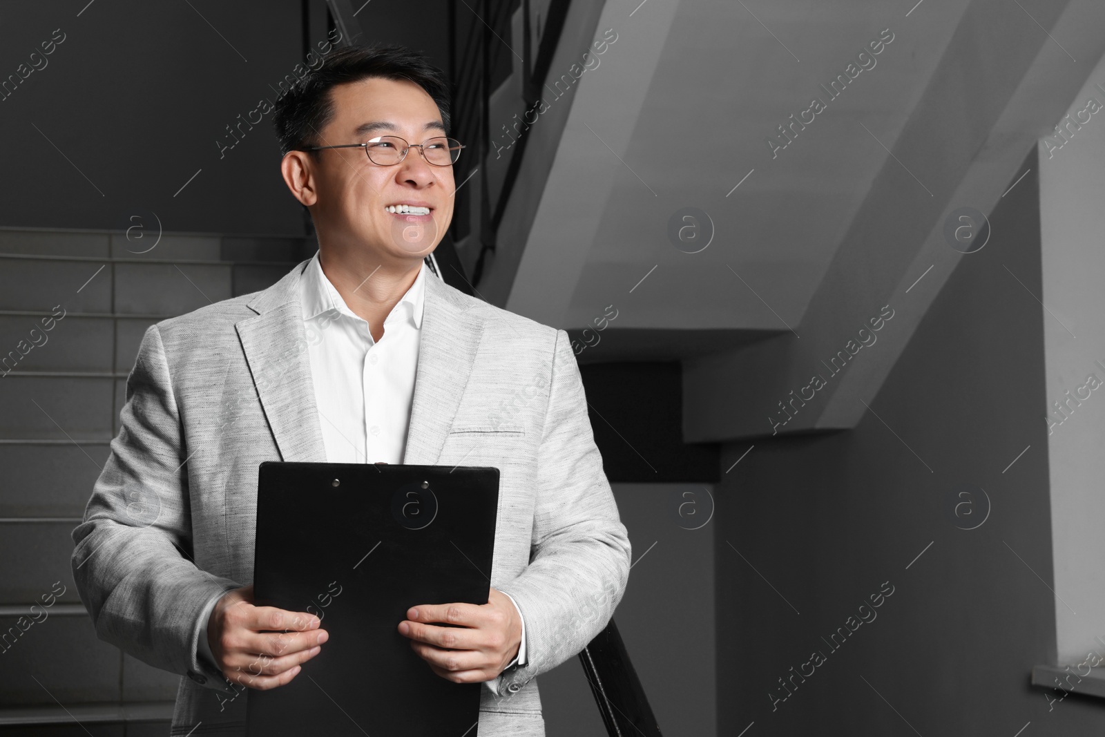 Photo of Happy boss with clipboard in office. Space for text