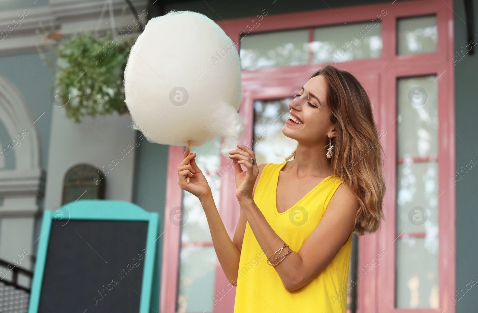 Photo of Happy young woman with cotton candy outdoors