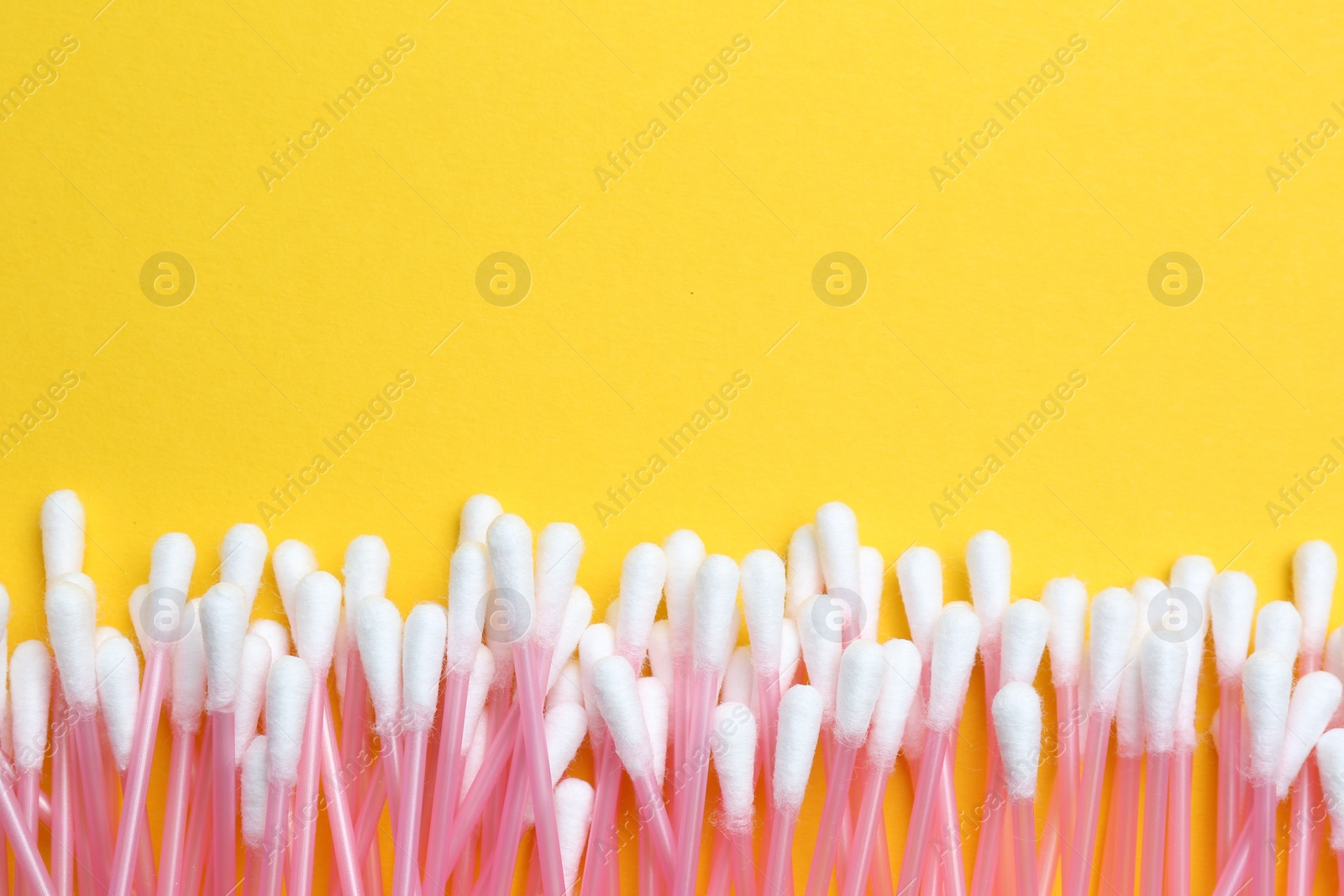 Photo of Many cotton buds on yellow background, flat lay. Space for text