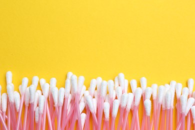 Many cotton buds on yellow background, flat lay. Space for text