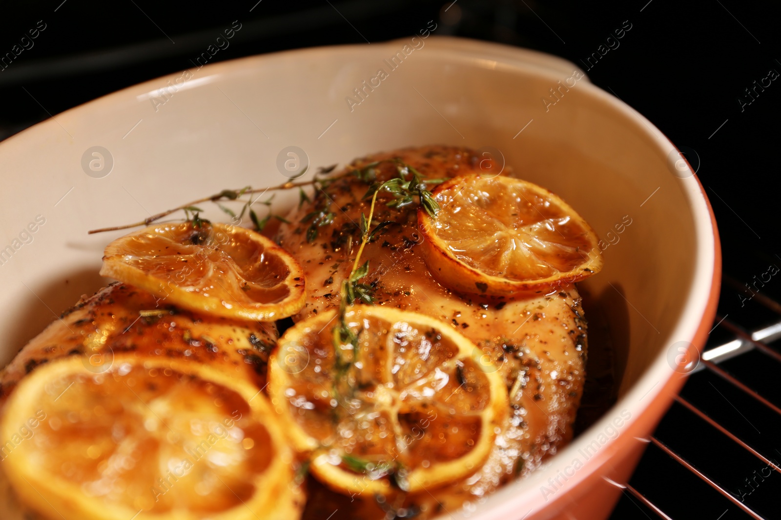 Photo of Baking dish with delicious lemon chicken in oven, closeup view