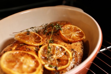 Photo of Baking dish with delicious lemon chicken in oven, closeup view