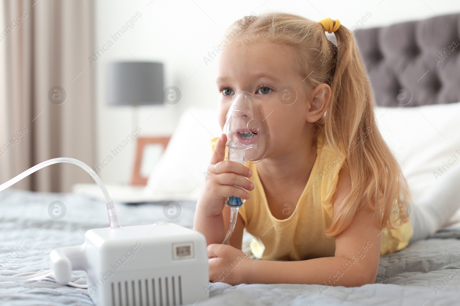 Photo of Little girl using asthma machine in bedroom. Space for text