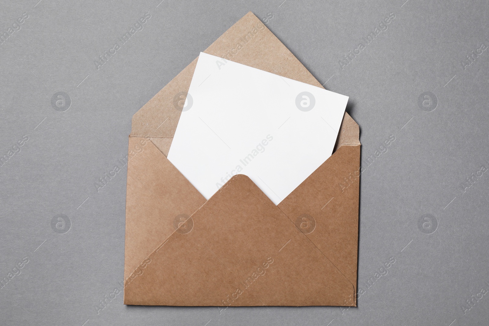 Photo of Blank sheet of paper in open letter envelope on grey background, top view