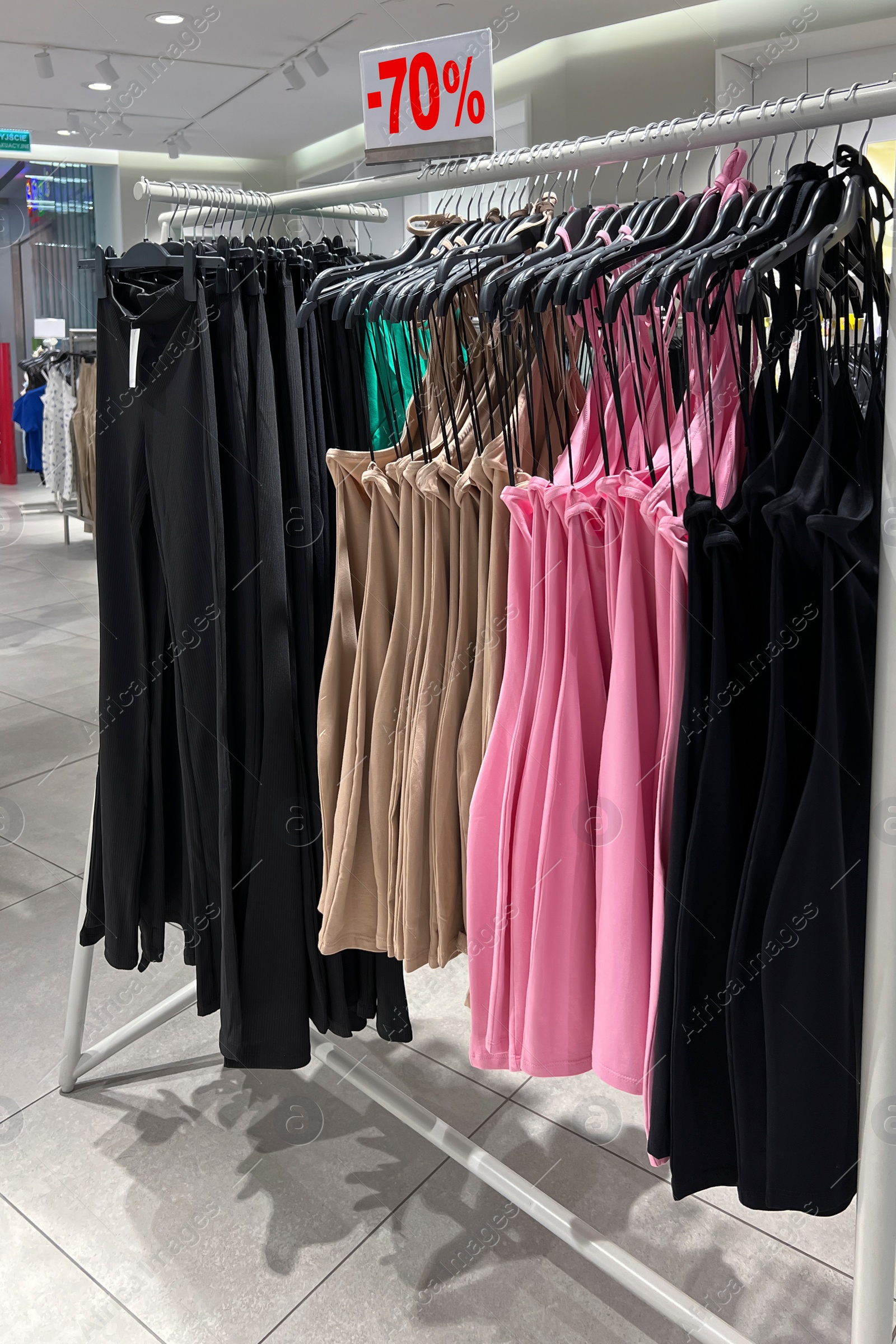 Image of Sale sign and rack with collection of stylish women's clothes in fashion store