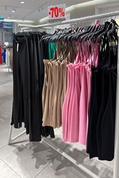 Image of Sale sign and rack with collection of stylish women's clothes in fashion store