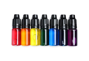 Bottles with different food coloring on white background, top view