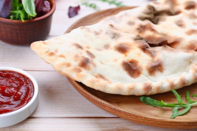 Photo of Delicious calzone on light wooden table, closeup