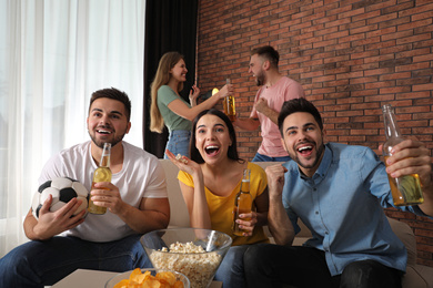 Group of friends watching football at home