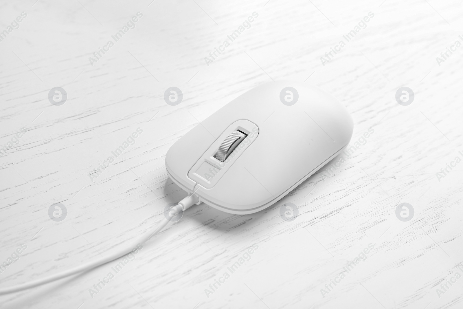 Photo of Modern wired optical mouse on white wooden table