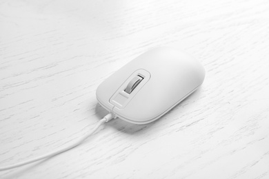 Modern wired optical mouse on white wooden table