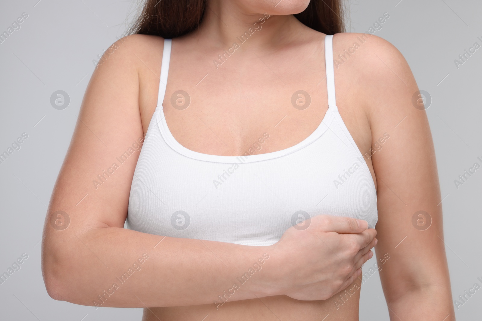 Photo of Mammology. Woman doing breast self-examination on light grey background, closeup