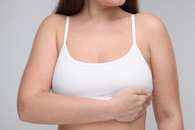 Mammology. Woman doing breast self-examination on light grey background, closeup