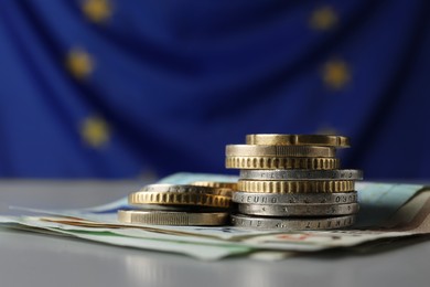 Photo of Coins and banknotes on table against European Union flag, closeup. Space for text