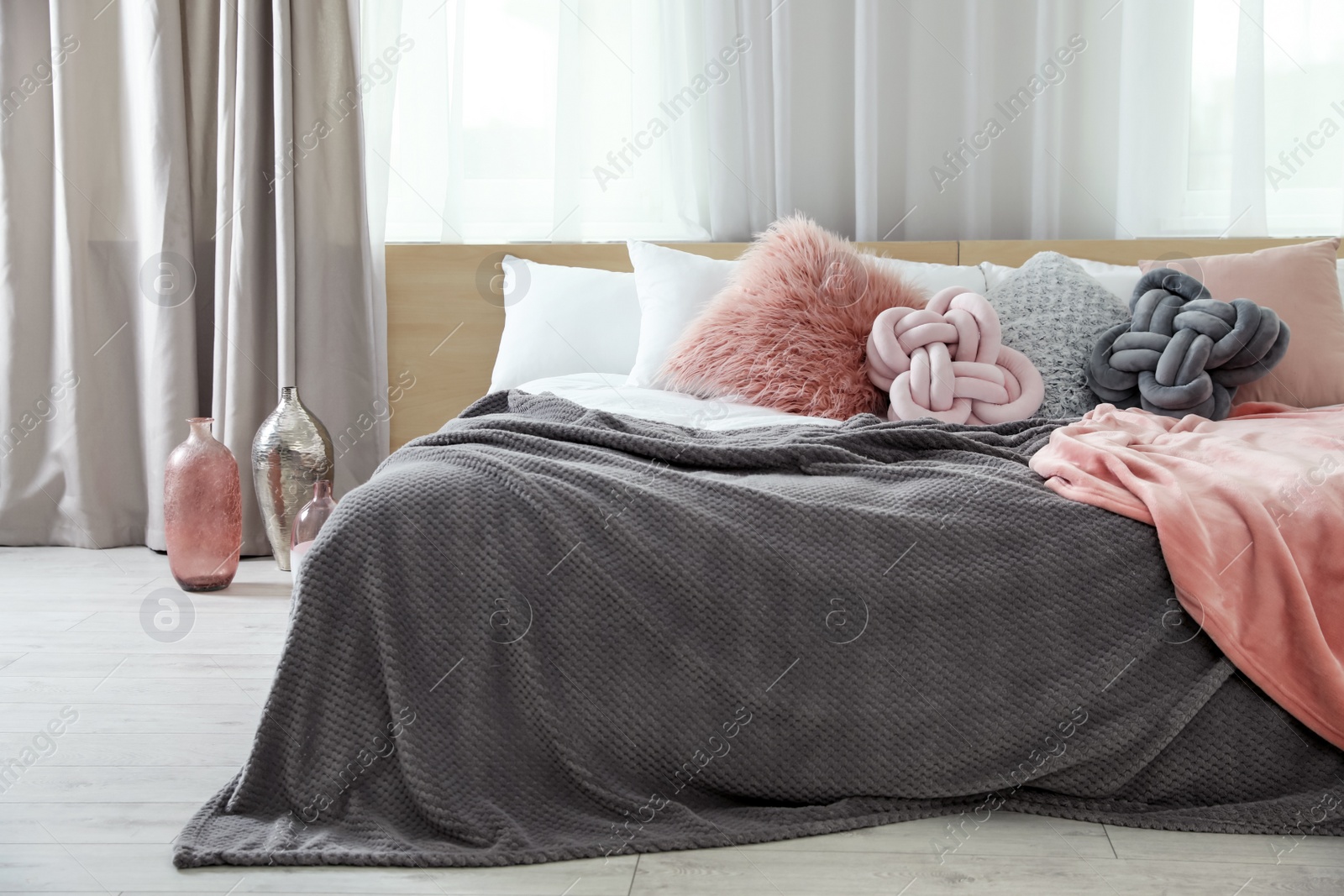 Photo of Comfortable bed with pillows and plaid in modern room interior