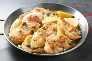 Delicious chicken piccata with lemons on grey table, closeup