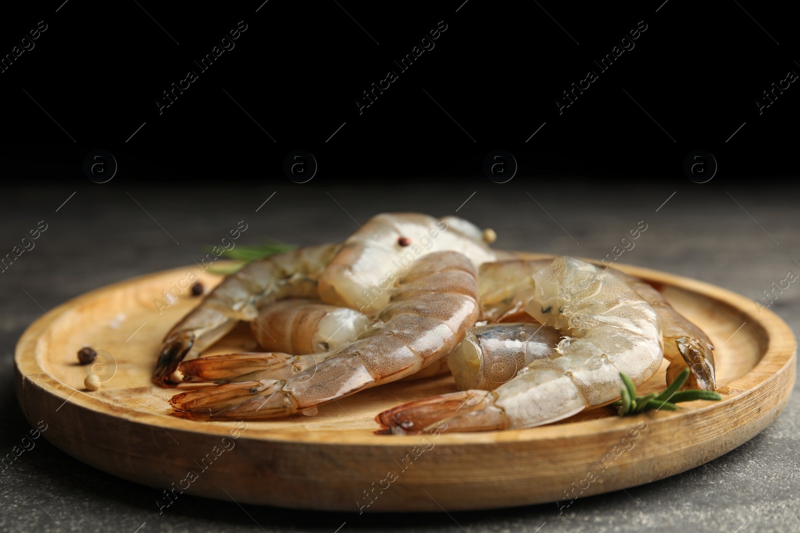 Photo of Fresh raw shrimps with rosemary on wooden board
