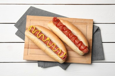 Delicious hot dogs with mustard and ketchup on white wooden table, top view