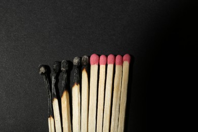 Burnt and whole matches on black background, flat lay. Stop destruction concept