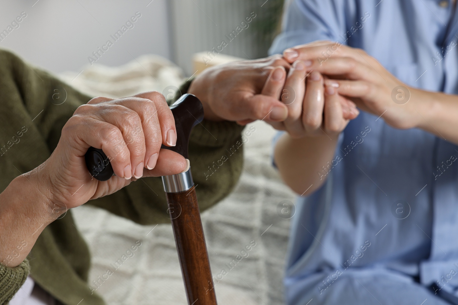 Photo of Caregiver and elderly woman with walking cane at home, closeup