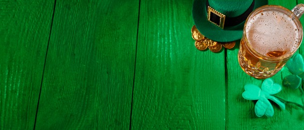 Image of St. Patrick's day. Beer, leprechaun hat, gold and decorative clover leaves on green wooden table. Banner design with space for text