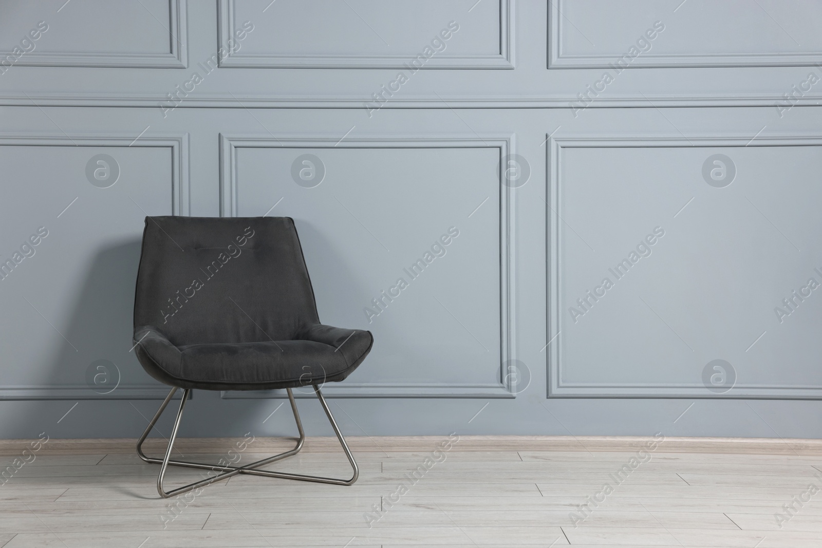 Photo of Comfortable armchair near grey wall in room, space for text