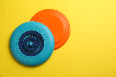 Photo of Plastic frisbee disks on yellow background, flat lay. Space for text