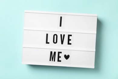 Light box with phrase I Love Me on blue background, top view