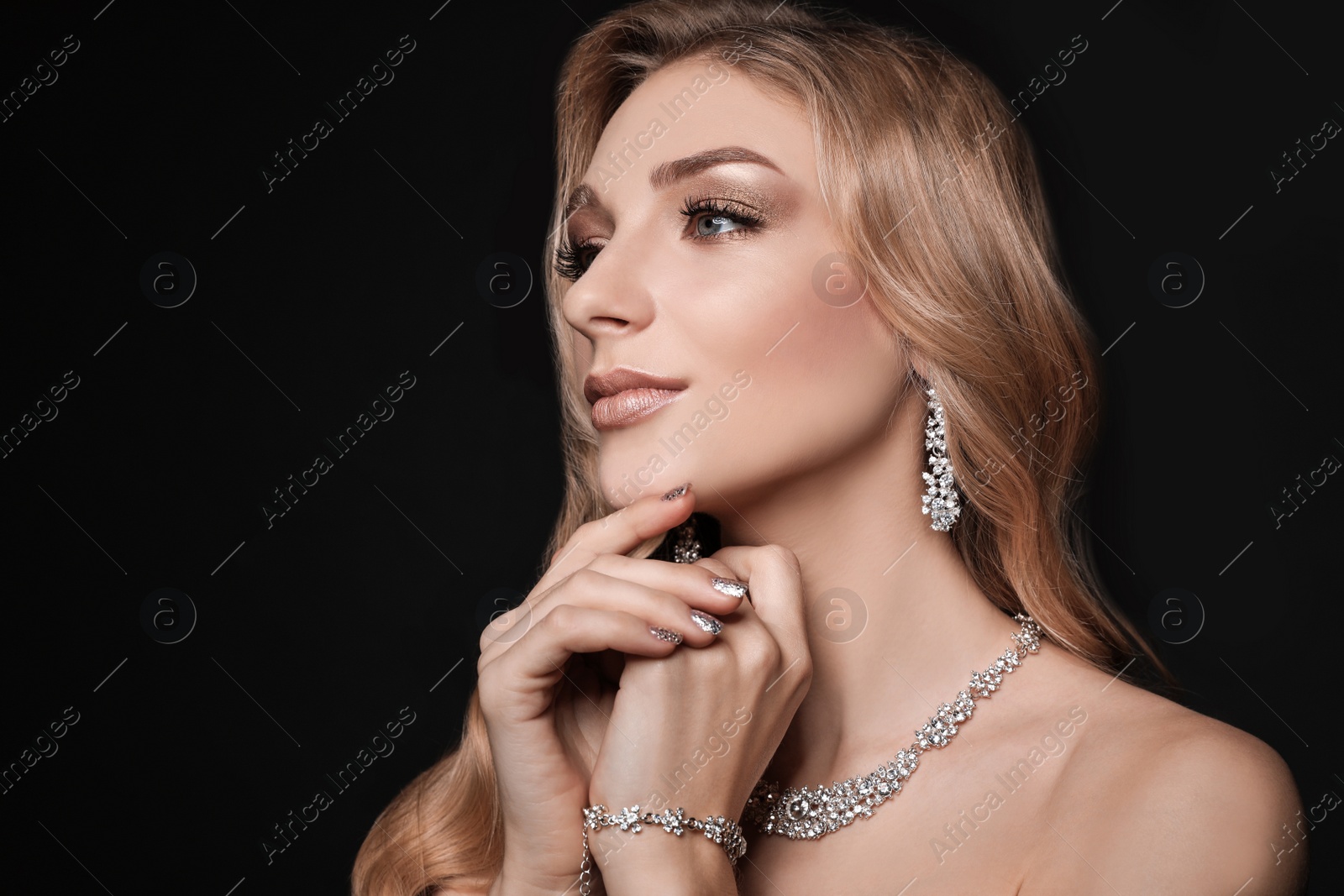 Photo of Beautiful young woman with elegant jewelry on dark background. Space for text