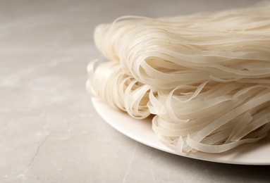 Photo of Plate with raw rice noodles on table, closeup. Space for text