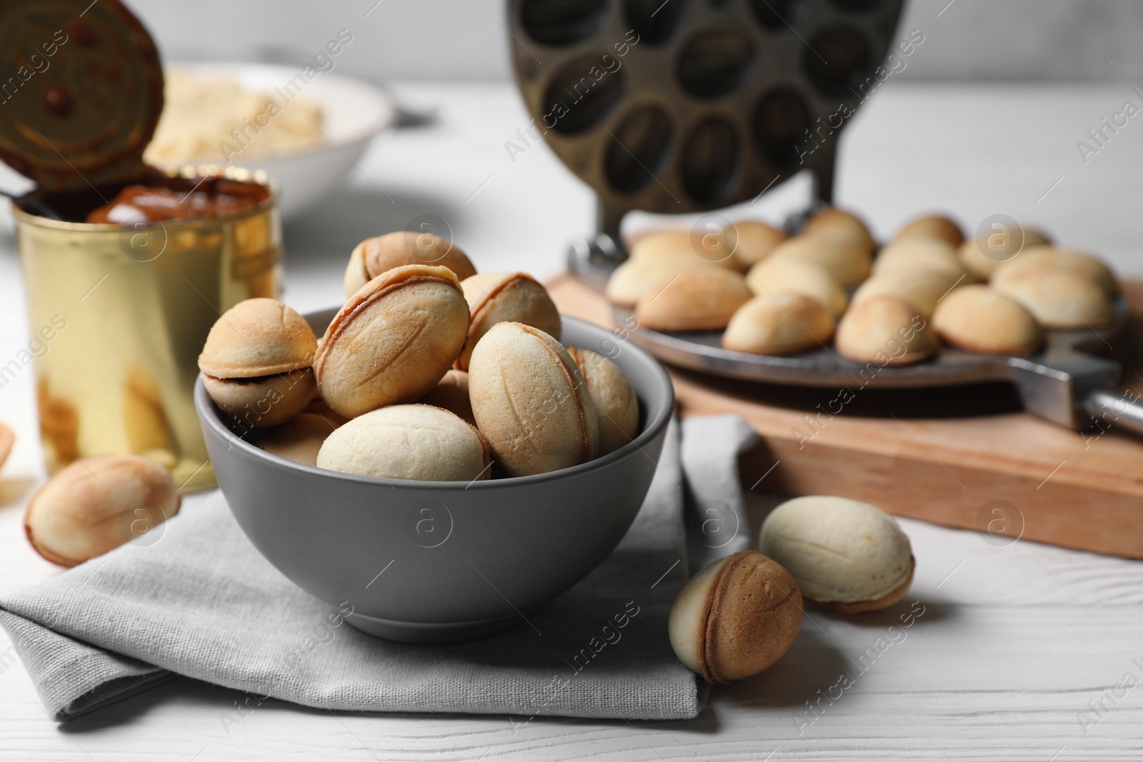 Photo of Delicious walnut shaped cookies with condensed milk on white wooden table, closeup