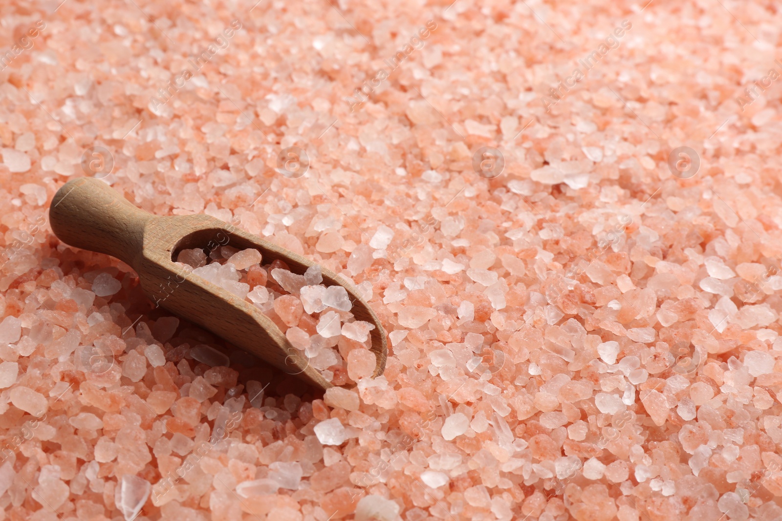 Photo of Pink himalayan salt and wooden scoop as background, closeup