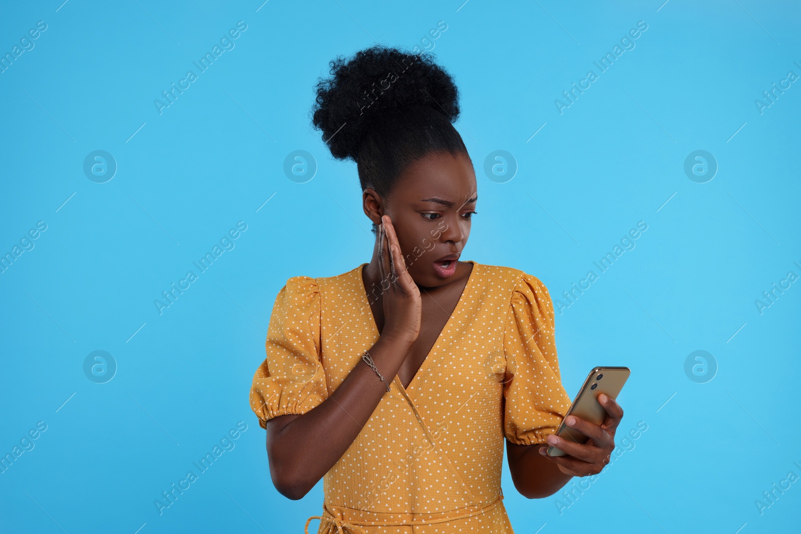 Photo of Emotional young woman with smartphone on light blue background