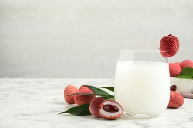 Photo of Lychee juice and fresh fruits on white marble table. Space for text