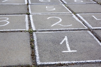 Photo of Hopscotch drawn with white chalk on street tiles outdoors, closeup