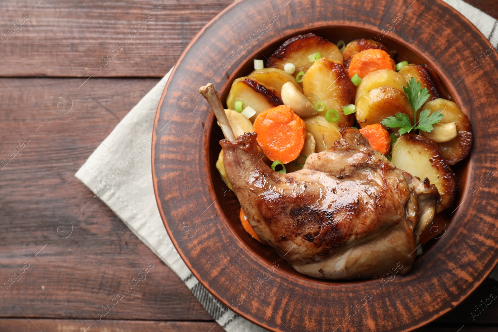 Photo of Tasty cooked rabbit meat with vegetables on wooden table, top view. Space for text