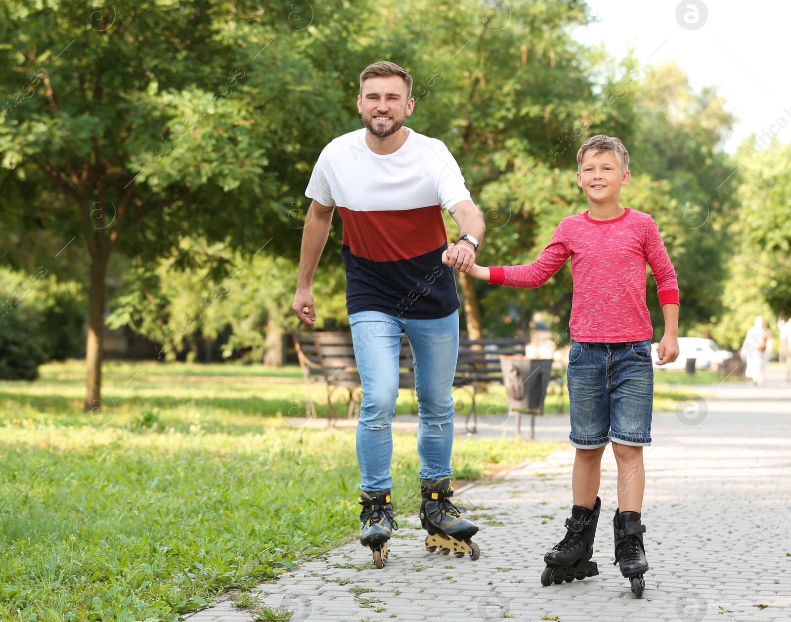 Photo of Father and son roller skating in summer park