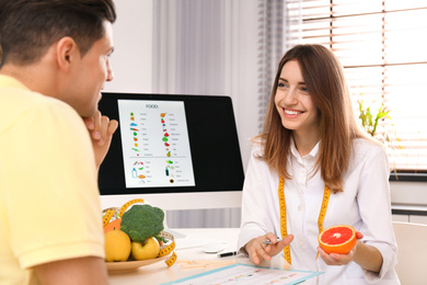 Photo of Young nutritionist consulting patient at table in clinic