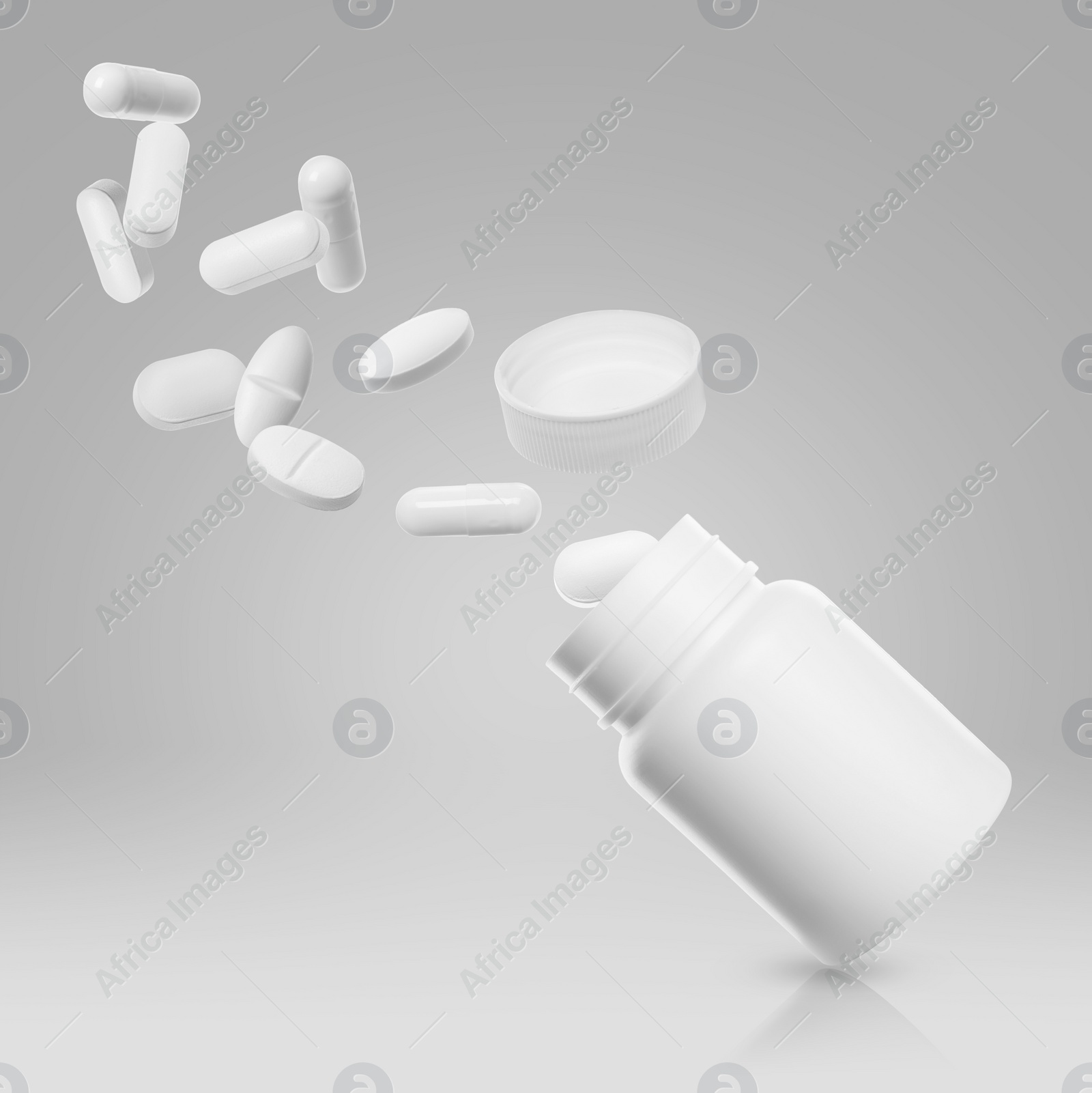 Image of Many different white pills falling into bottle on light grey background