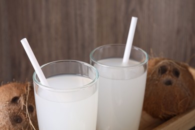 Photo of Glasses of coconut water with straws and nuts on table, closeup