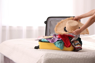 Woman packing suitcase for journey at home, closeup. Space for text