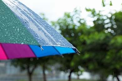 Photo of Colorful umbrella outdoors on rainy day, closeup