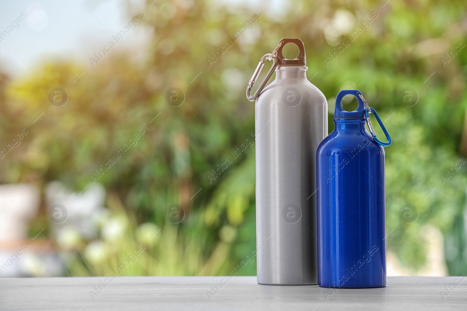 Photo of Sports water bottles on table against blurred background. Space for text