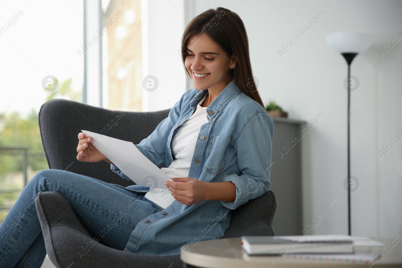 Photo of Young woman reading paper letter at home