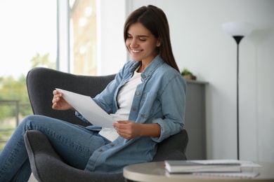 Young woman reading paper letter at home